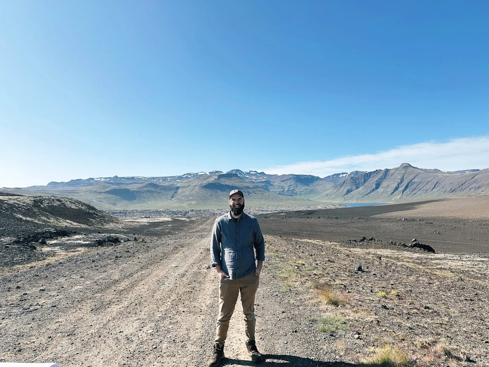 Jake standing on a gravel road in a wide, empty landscape with mountains behind